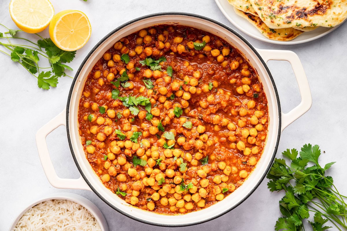 Pot filled with chickpeas simmered in a spiced tomato sauce, topped with fresh cilantro.