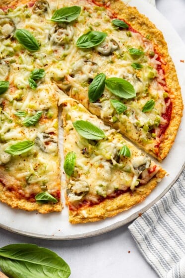 Chicken crust pizza topped with melted mozzarella and basil leaves.