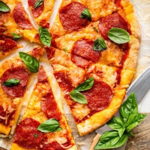 Sliced pepperoni pizza with crispy cottage cheese crust topped with fresh basil.