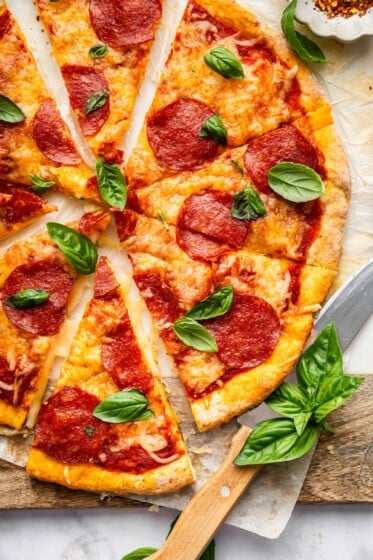 Sliced pepperoni pizza with crispy cottage cheese crust topped with fresh basil.