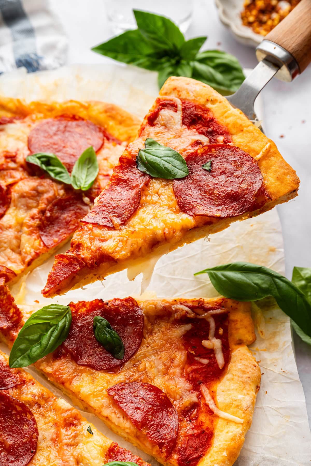 Sliced cottage cheese pizza crust with pepperoni topped with fresh basil.
