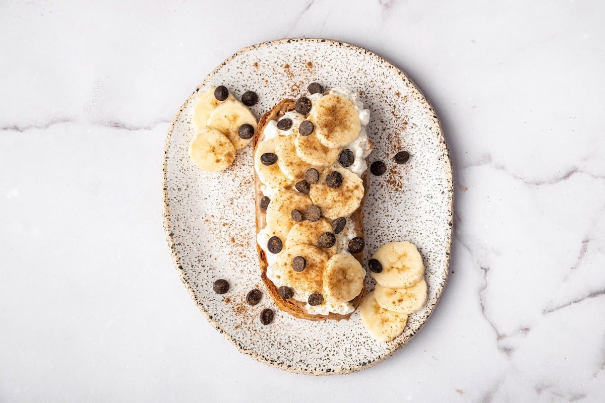 Cottage cheese toast topped with sliced banana, mini chocolate chips, and a sprinkle of cinnamon.