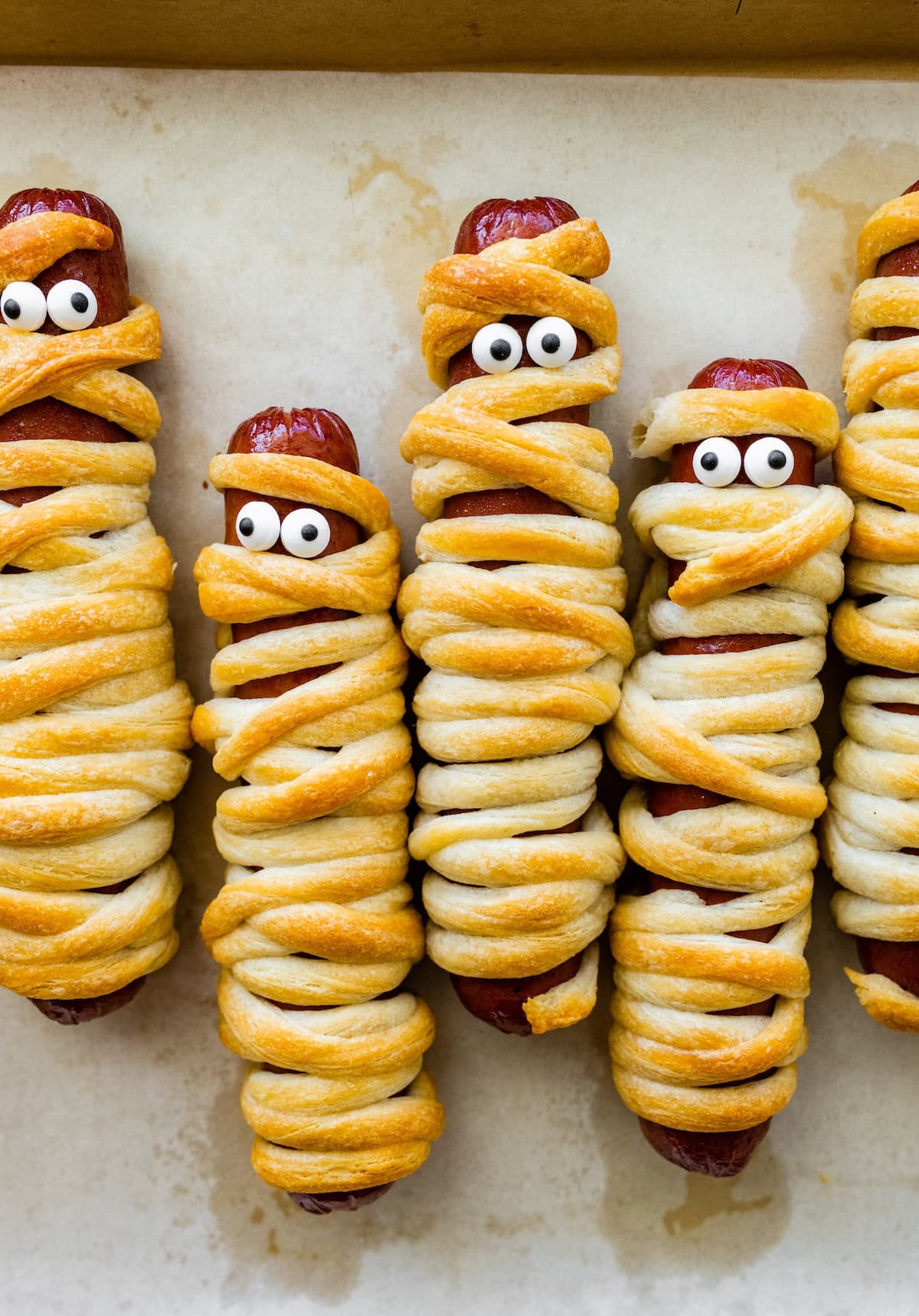 Baked mummy hot dogs wrapped in crescent roll “bandages” with candy eyes.