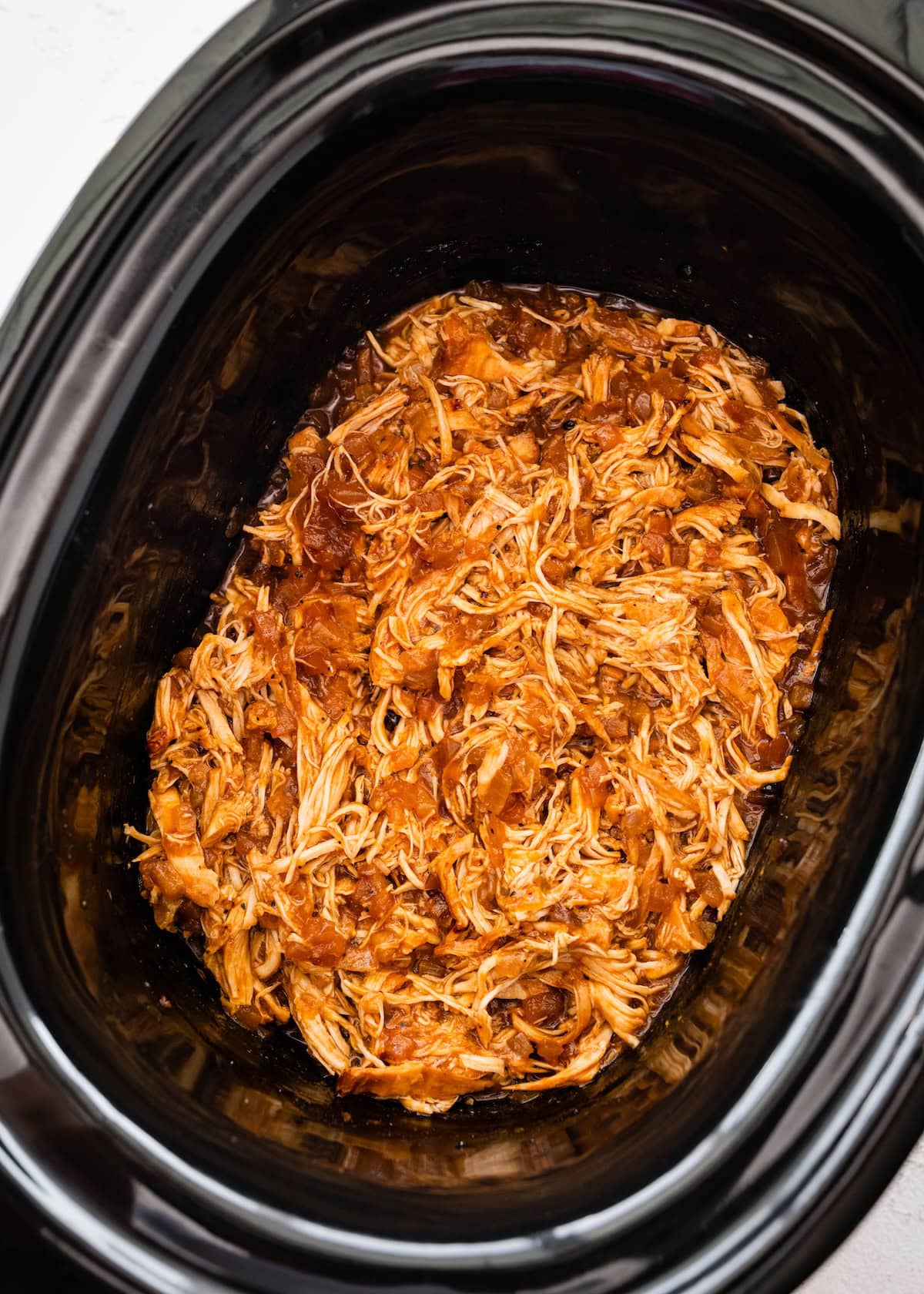 Cooked shredded apple BBQ chicken in a slow cooker.