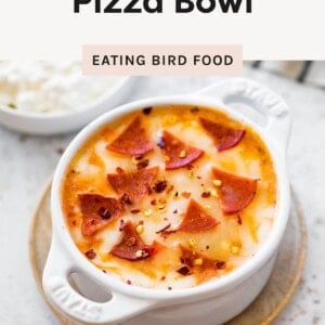 A small white dish filled with melted cottage cheese pizza bowl topped with pepperoni slices and red pepper flakes.