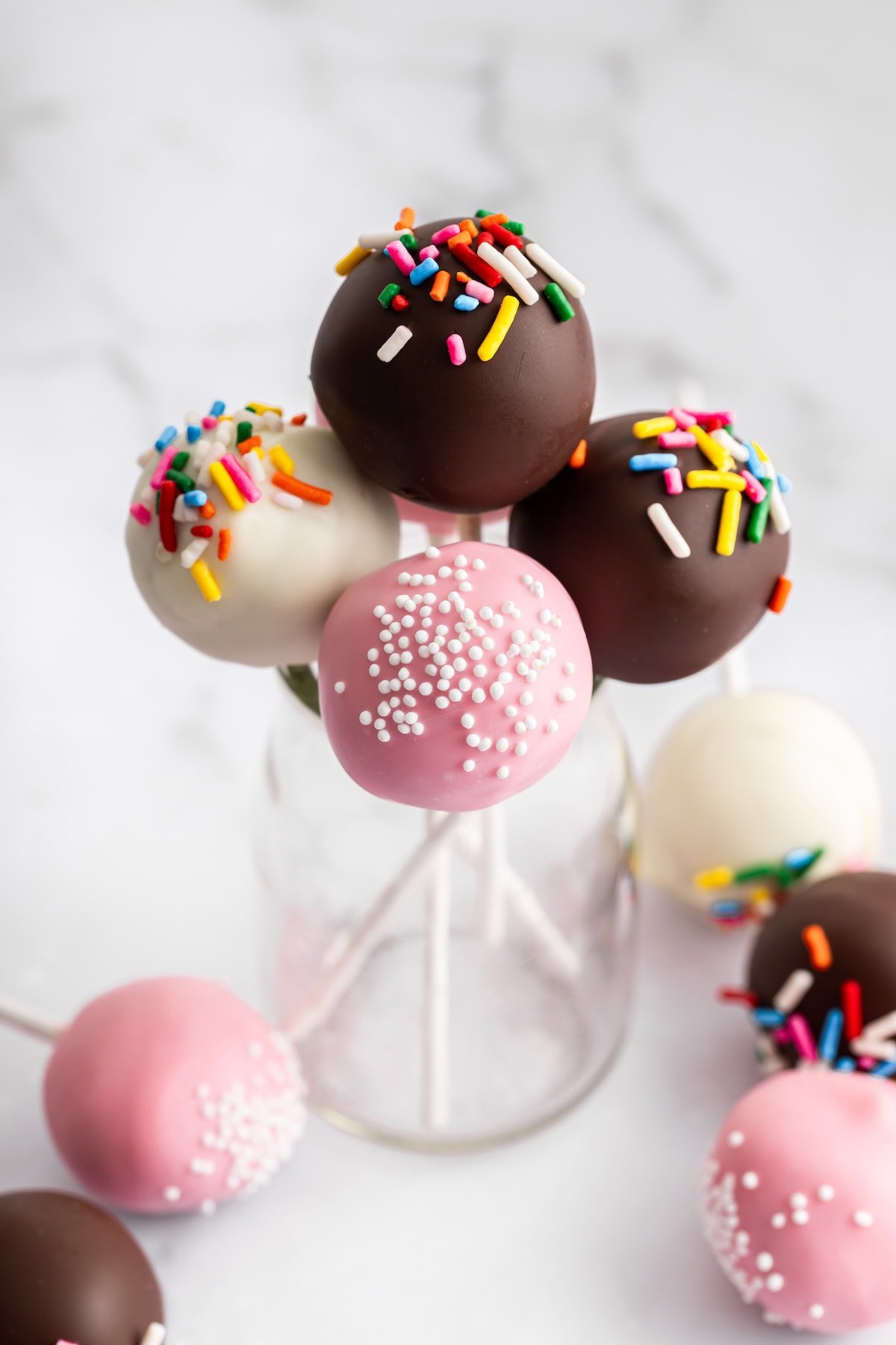 Chocolate and pink cake pops in a glass vase for serving.