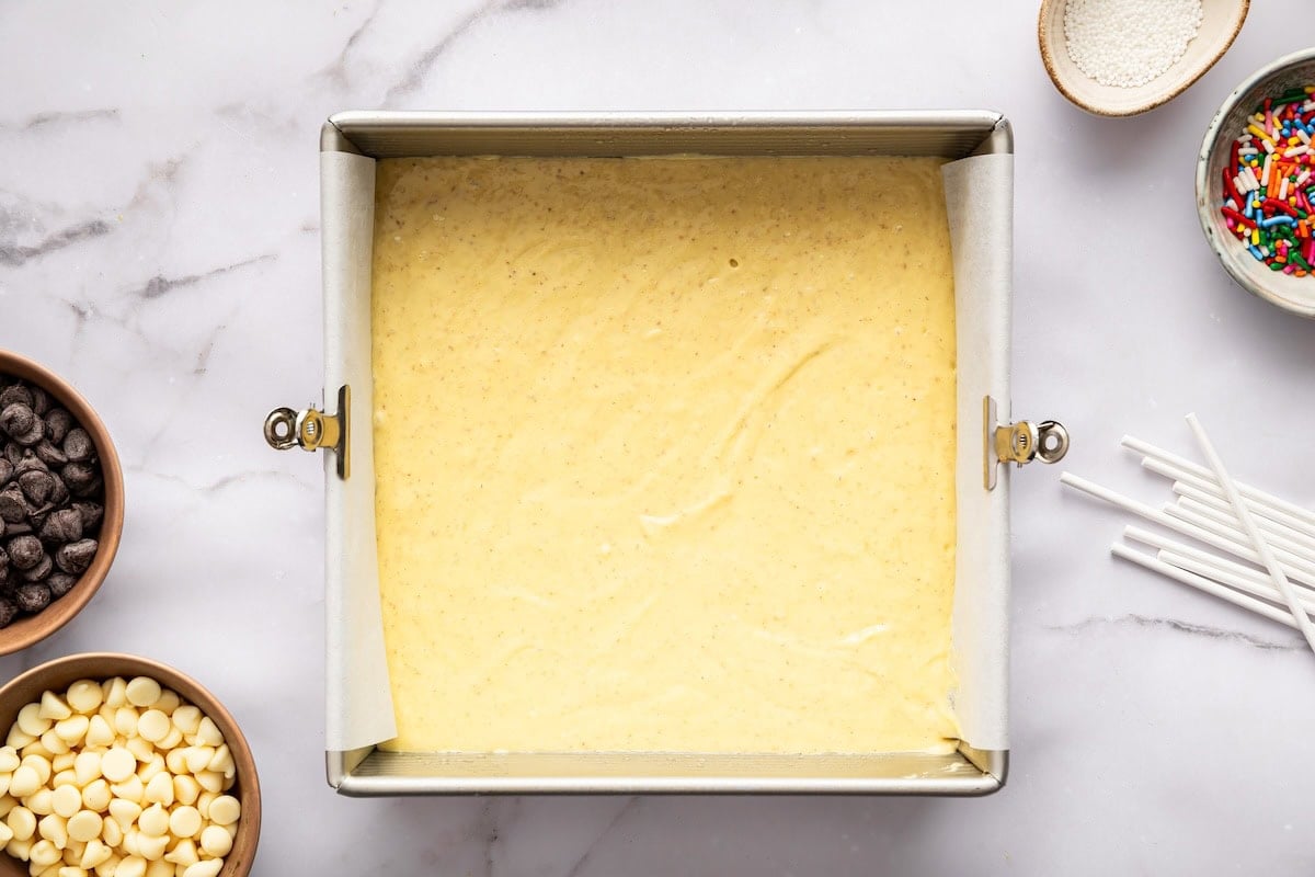 Cake batter spread evenly in a square pan before baking.