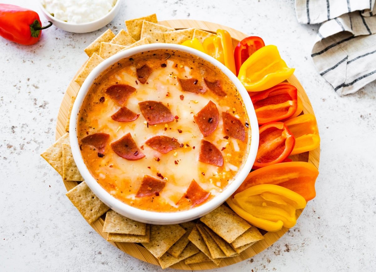 High protein cottage cheese pizza bowl surrounded by sliced bell peppers and crackers, ready to serve.