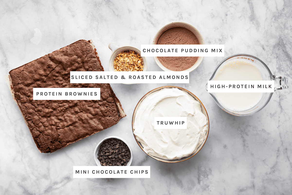 Protein Brownies, Sliced Salted & Roasted Almonds, Chocolate Pudding Mix, High-Protein Milk, Truwhip, and Mini Chocolate Chips.