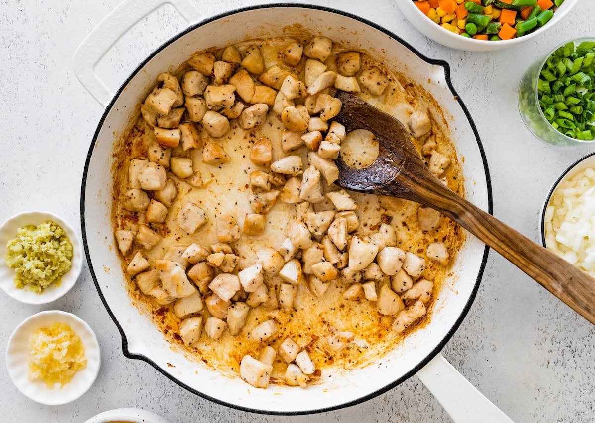 Chicken pieces sautéing in a skillet until golden brown and cooked through.