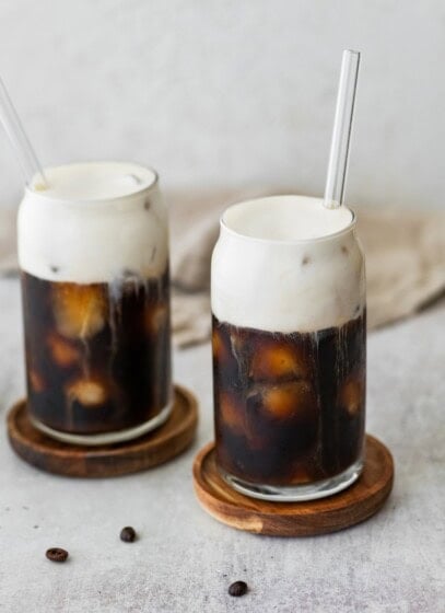Two glasses of iced coffee with protein cold foam on top.