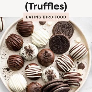 Plate of assorted chocolate-coated Oreo truffles with drizzle and crushed Oreo topping, arranged beside whole Oreo cookies.