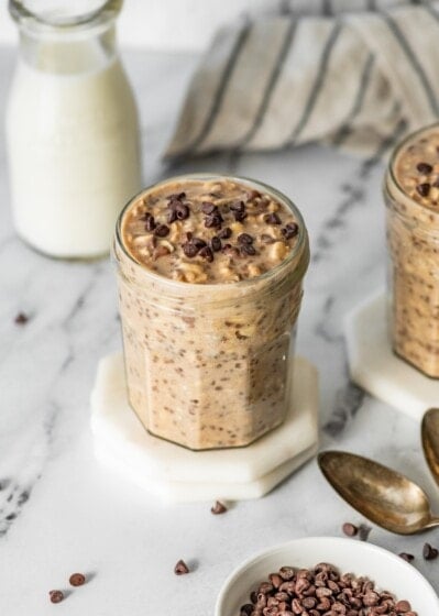 Single jar of cookie dough overnight oats topped with chocolate chips on a white coaster.