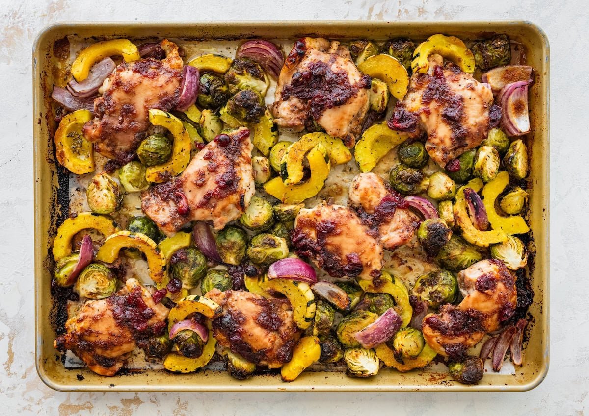 Golden roasted chicken thighs, Brussels sprouts, and squash on a sheet pan fresh from the oven.