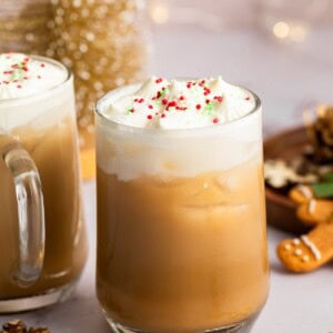 Iced sugar cookie latte topped with whipped cream and holiday sprinkles on a granite counter.