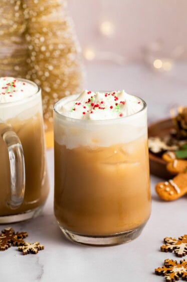 Iced sugar cookie latte topped with whipped cream and holiday sprinkles on a granite counter.