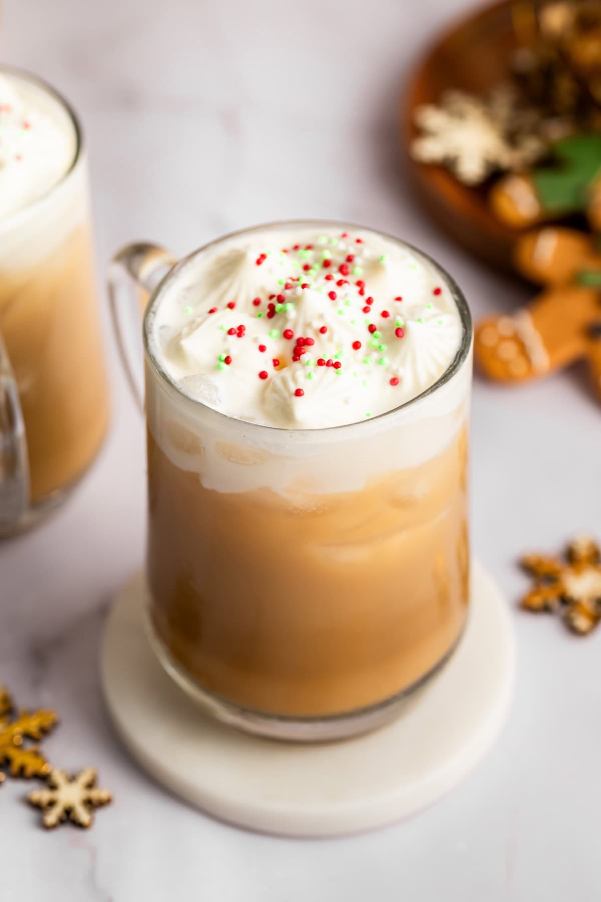 Iced sugar cookie latte topped with whipped cream and festive sprinkles in a clear mug.