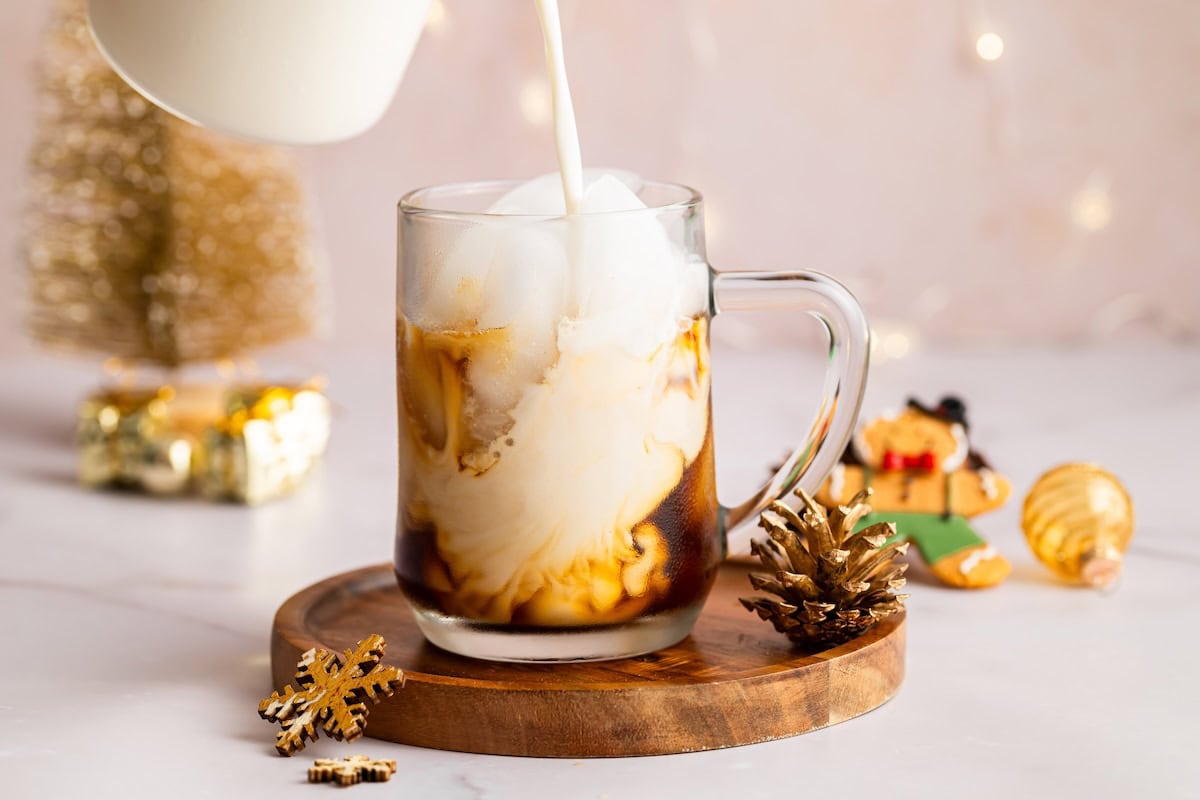 Almond milk being poured into an iced sugar cookie latte, creating a swirled creamy effect.