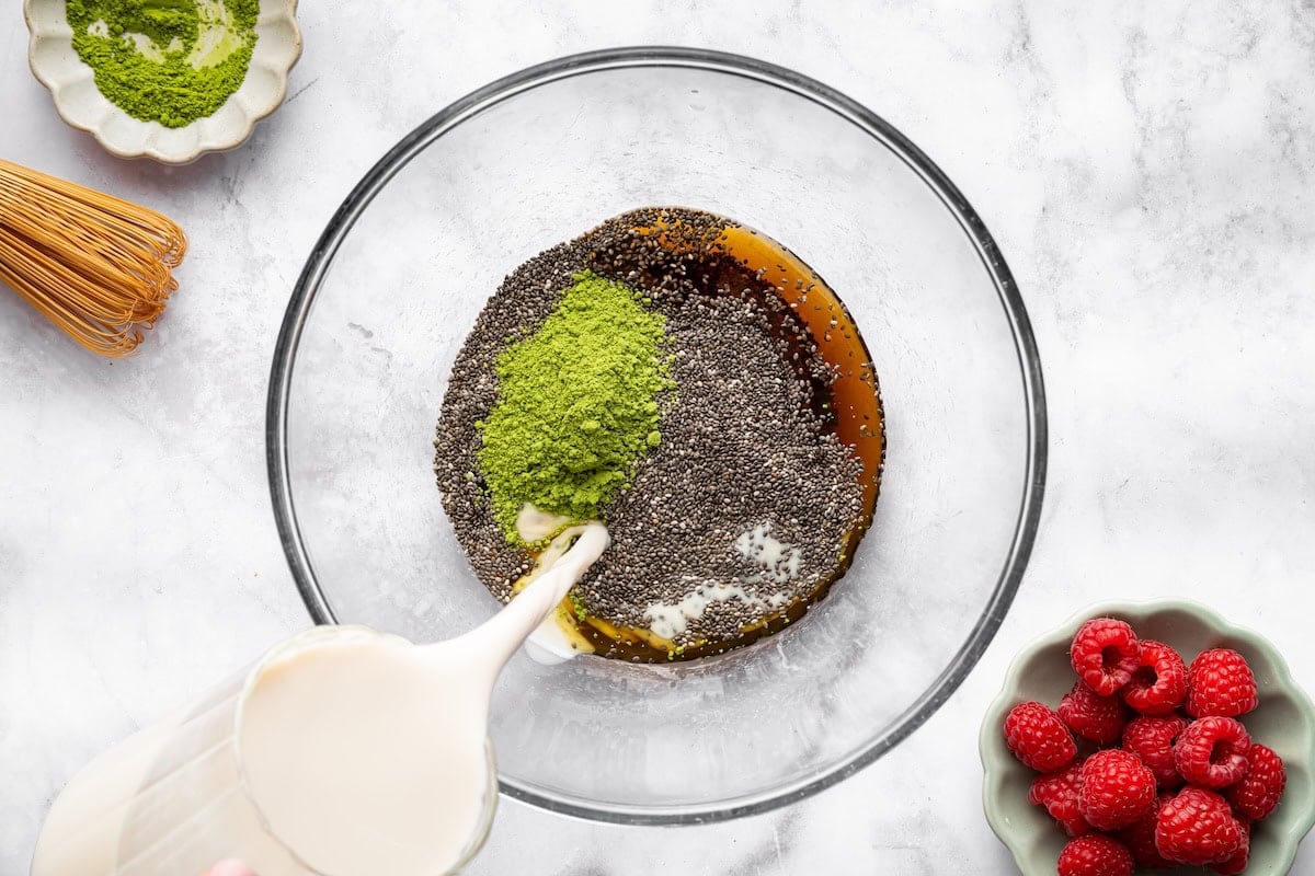 Chia seeds mixed with matcha, almond milk, maple syrup, and vanilla in a glass bowl.