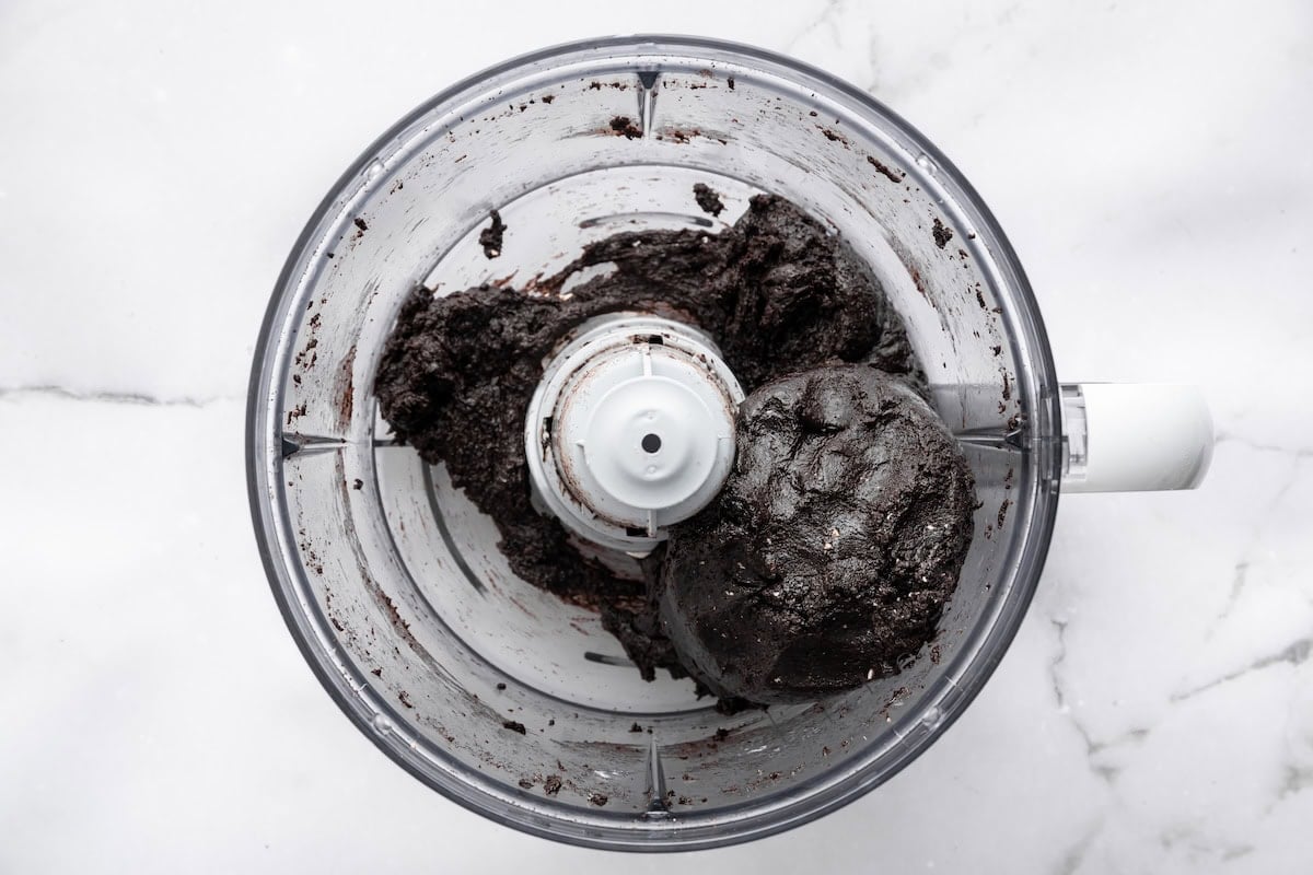 Blended Oreo truffle mixture forming a smooth dough inside a food processor.