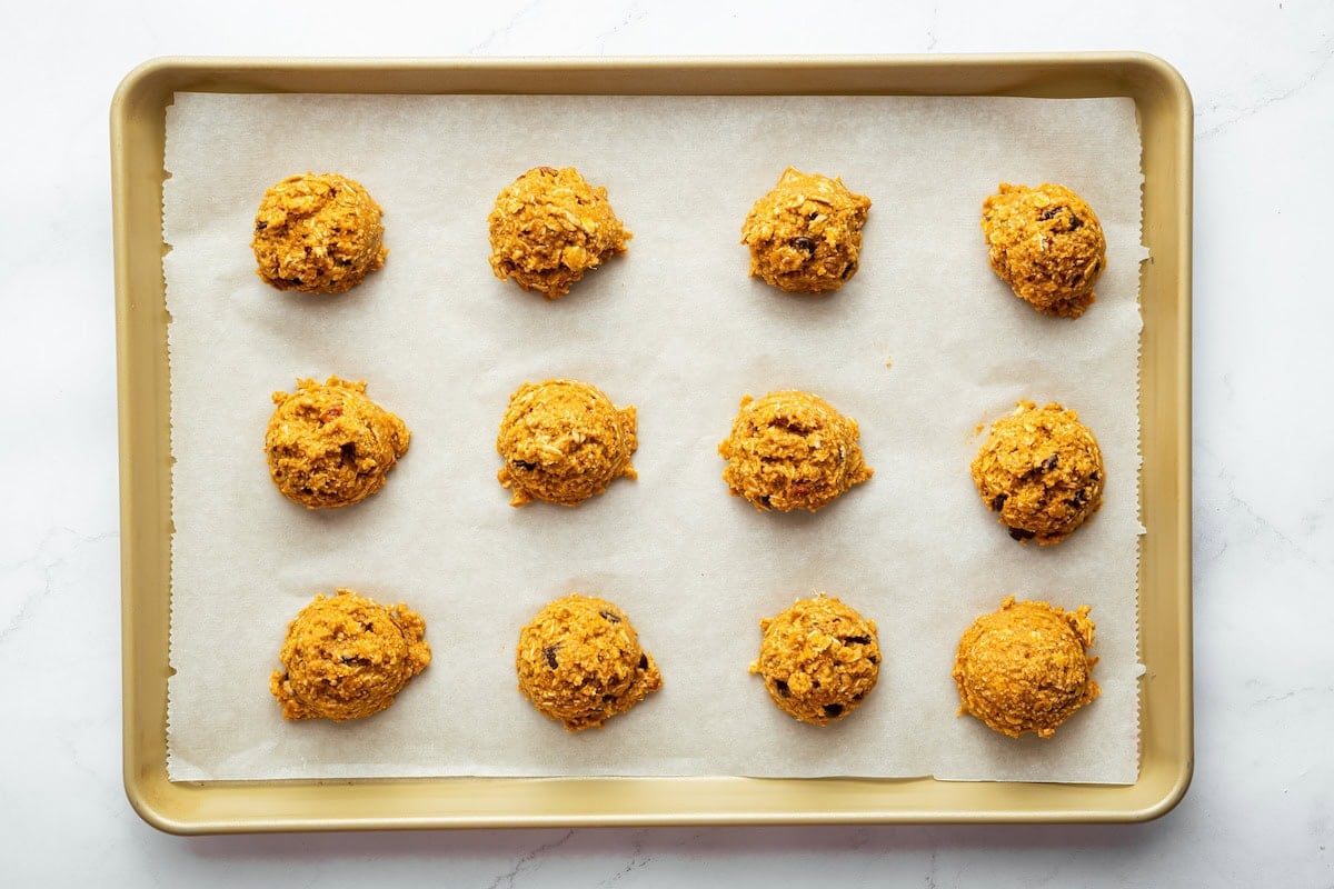 Twelve scoops of sweet potato breakfast cookies arranged on a baking sheet before baking.