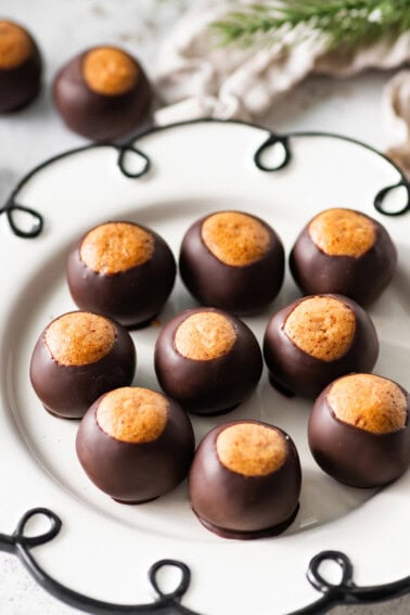 High-protein healthy buckeyes arranged on a white decorative plate with the peanut butter tops showing.