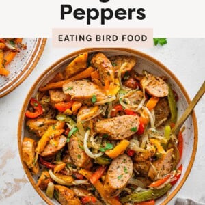 Bowl of sliced sausage with roasted bell peppers and onions, garnished with herbs.