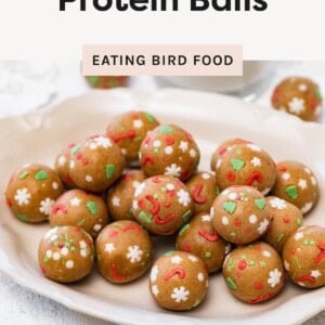 Sugar cookie protein balls piled on a plate, decorated with colorful holiday sprinkles