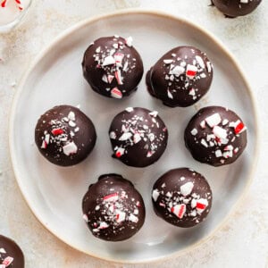 Plate of seven chocolate peppermint protein balls topped with crushed candy canes.