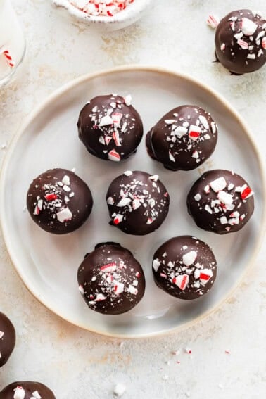 Plate of seven chocolate peppermint protein balls topped with crushed candy canes.