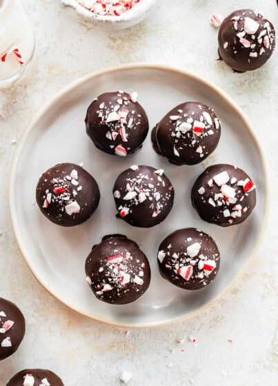 Plate of seven chocolate peppermint protein balls topped with crushed candy canes.