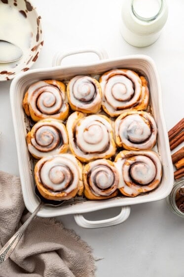 Protein cinnamon rolls in a square baking dish topped with an icing.