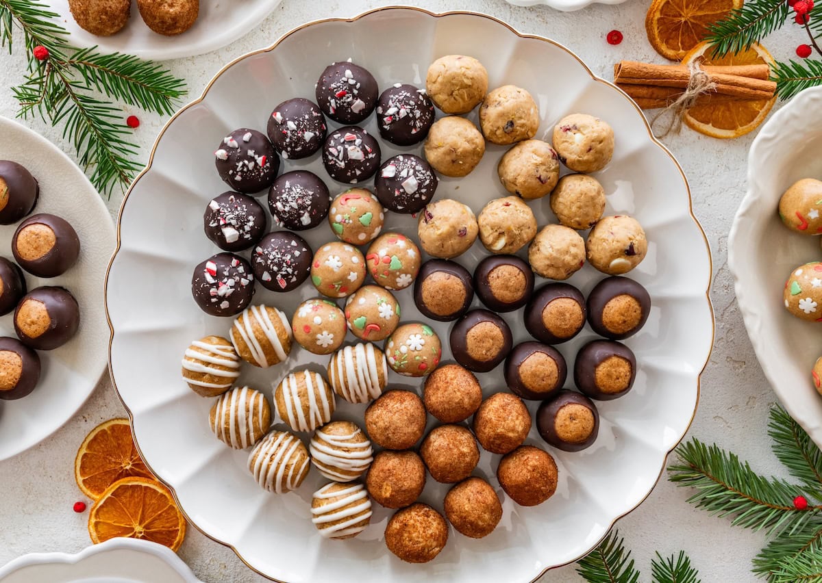 6 varieties of holiday protein balls on a white serving platter with gold trim.