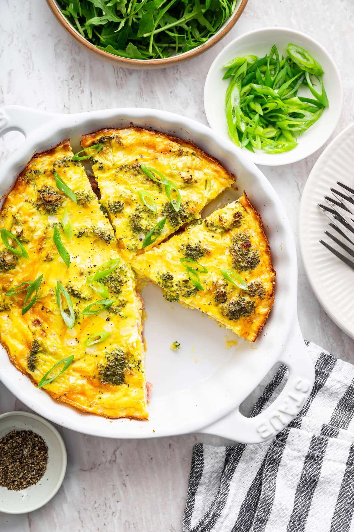 A crustless quiche cut into sizable portions in a round baking dish.