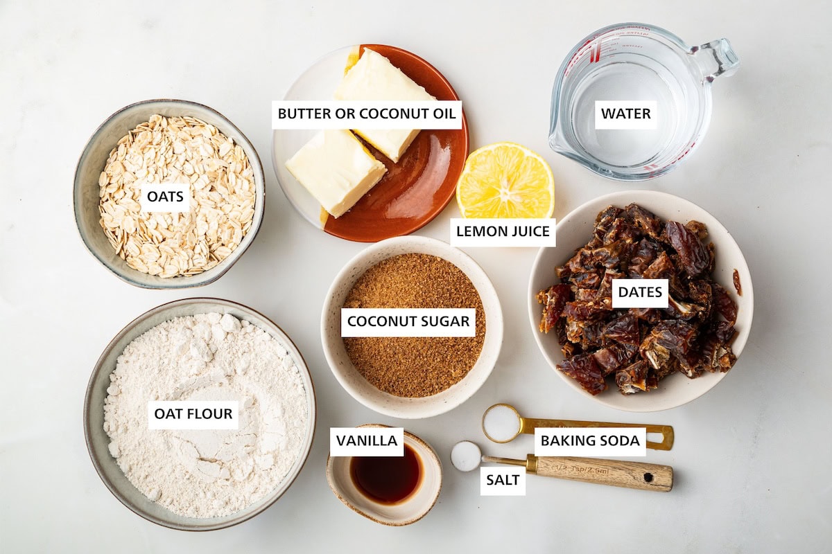 Ingredients measured out to make Date Bars: oat flour, oats, vanilla, coconut sugar, butter, lemon juice, baking soda, salt, dates and water.