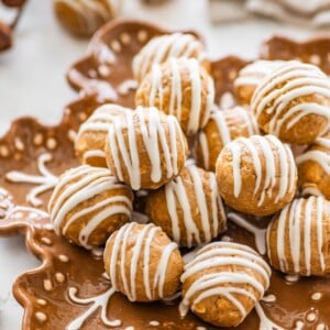 Close-up of gingerbread protein balls with white chocolate drizzle piled on a plate for serving.