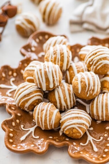 Close-up of gingerbread protein balls with white chocolate drizzle piled on a plate for serving.