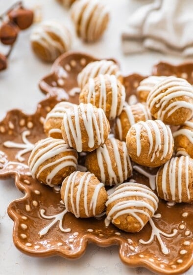 Close-up of gingerbread protein balls with white chocolate drizzle piled on a plate for serving.