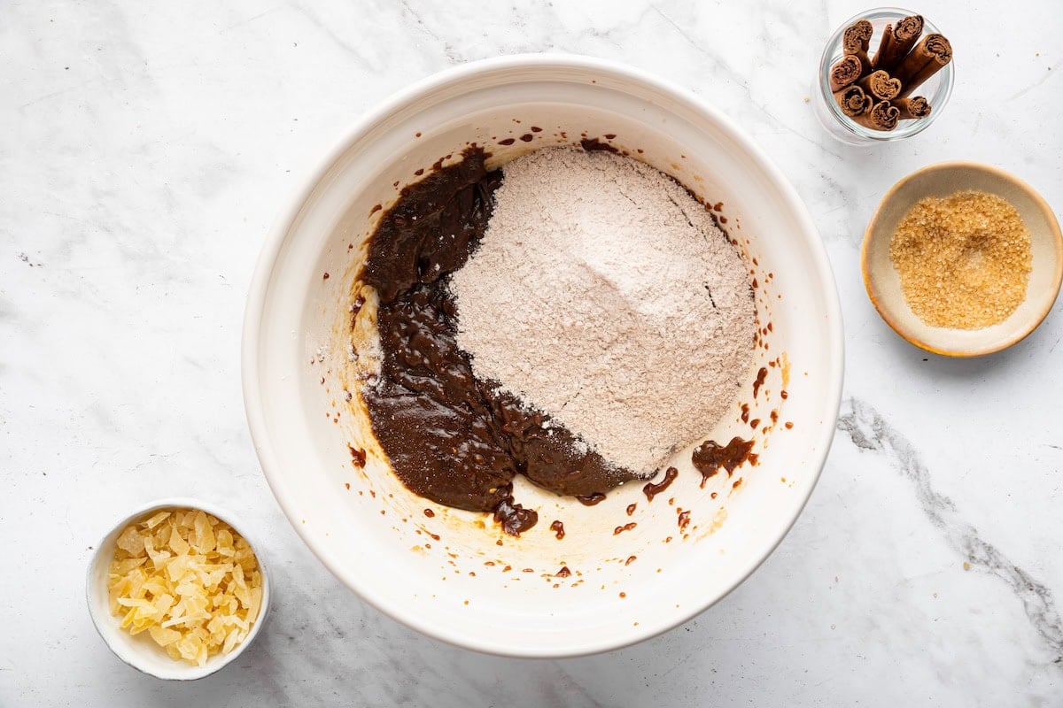 Dry ingredients used for gingersnap cookies added to a bowl of wet ingredients.