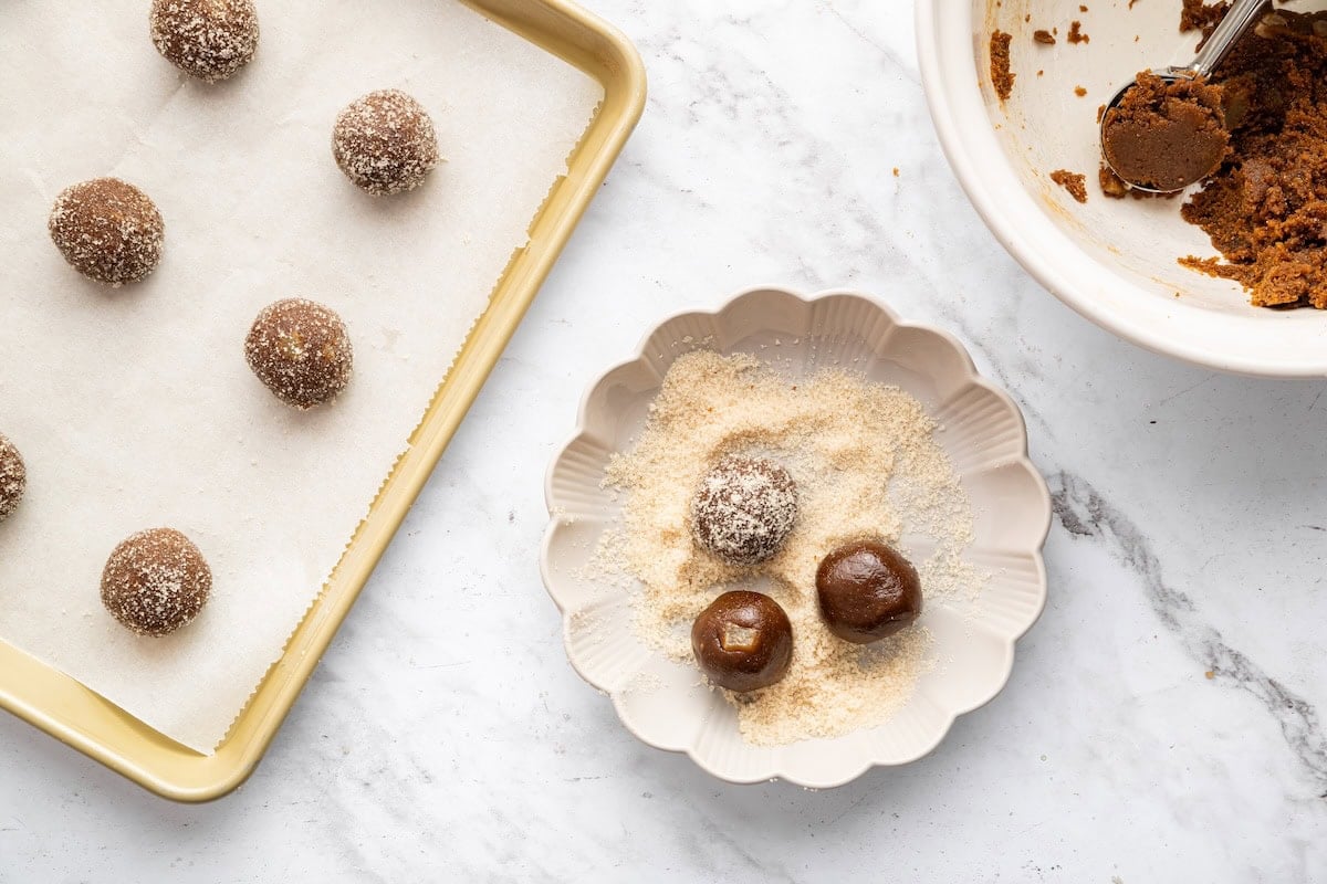 Gingersnap cookie dough rolled into balls and added to a small dish of cane sugar.