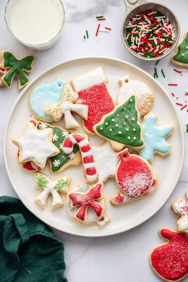 A plate filled with decorated holiday sugar cookies—trees, bows, snowflakes, ornaments, and candy canes.