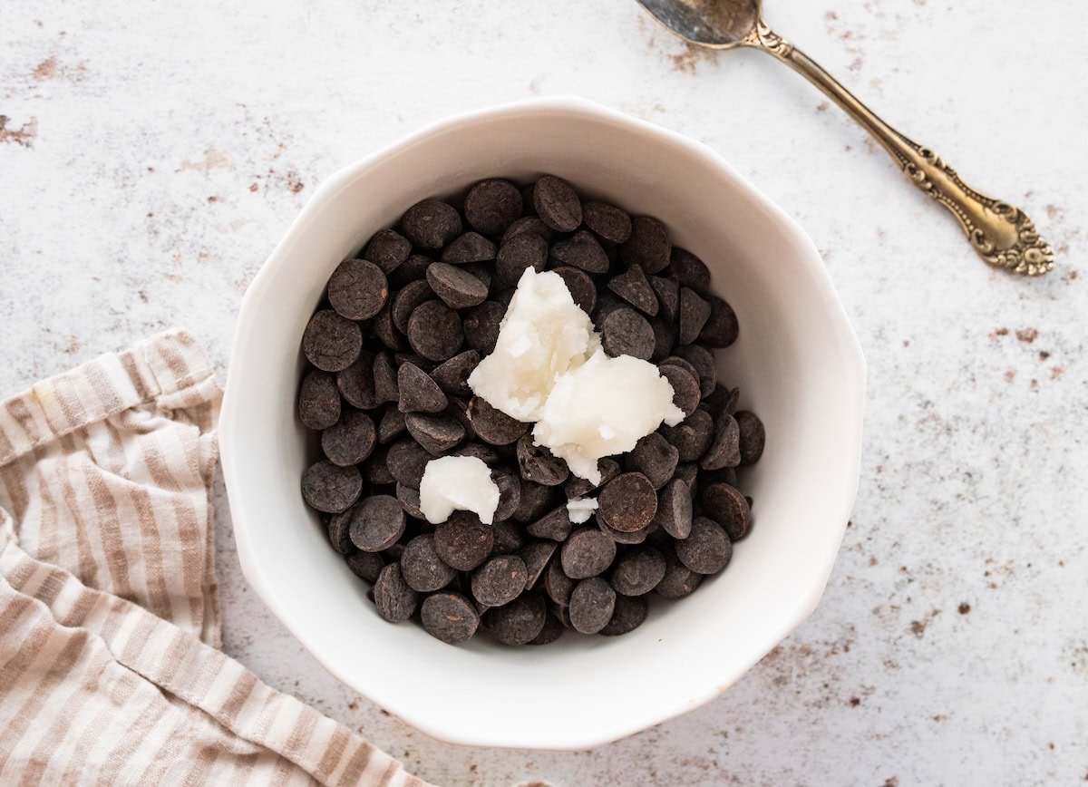 Dark chocolate chips and coconut oil in a white bowl before melting for coating the buckeyes.