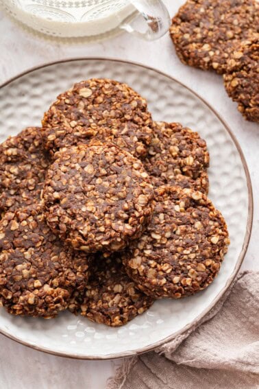 Multiple chocolate no bake cookies stacked on one another on a white plate.