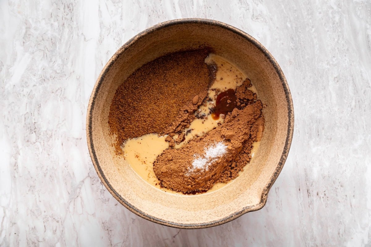 Dry ingredients like cocoa powder and sugar added to the wet ingredients used to make no bake cookies.