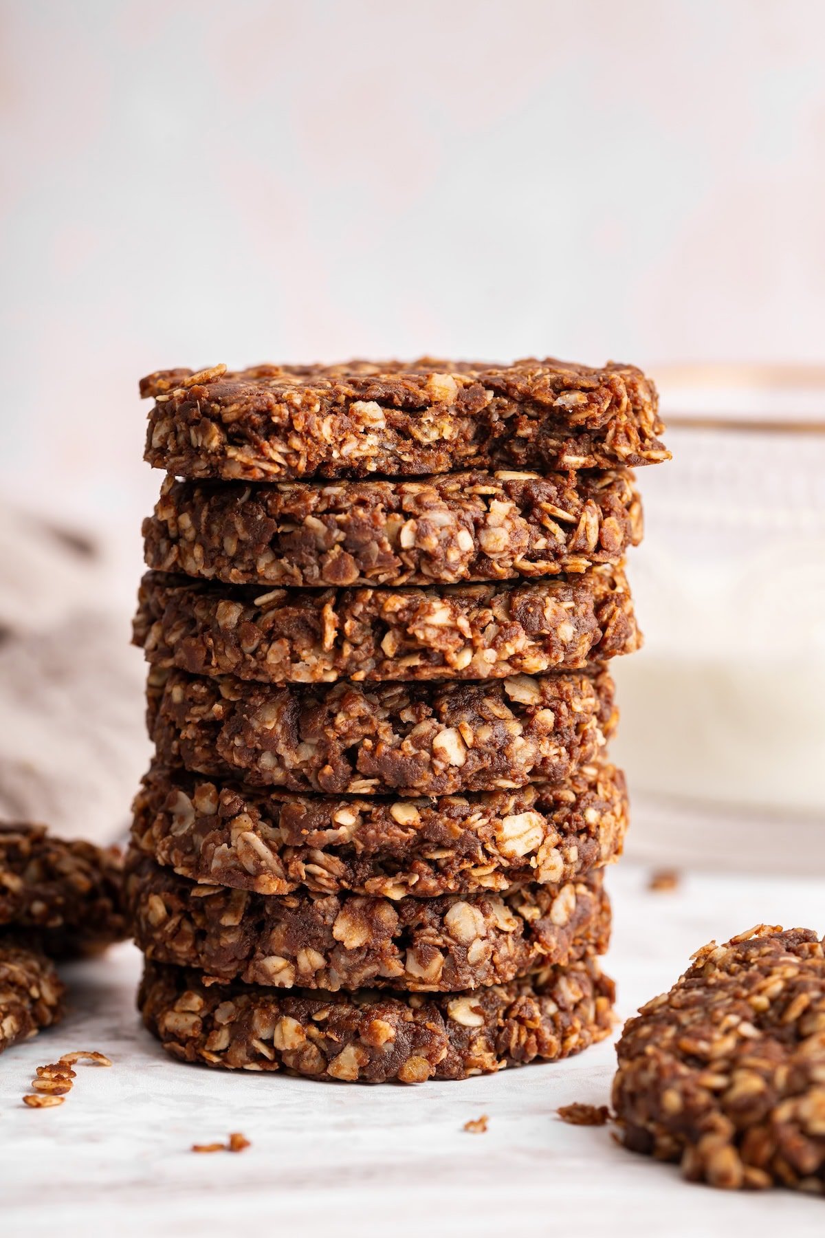 Seven no bake cookies stacked on one another with the top cookie having a bite taken from it.