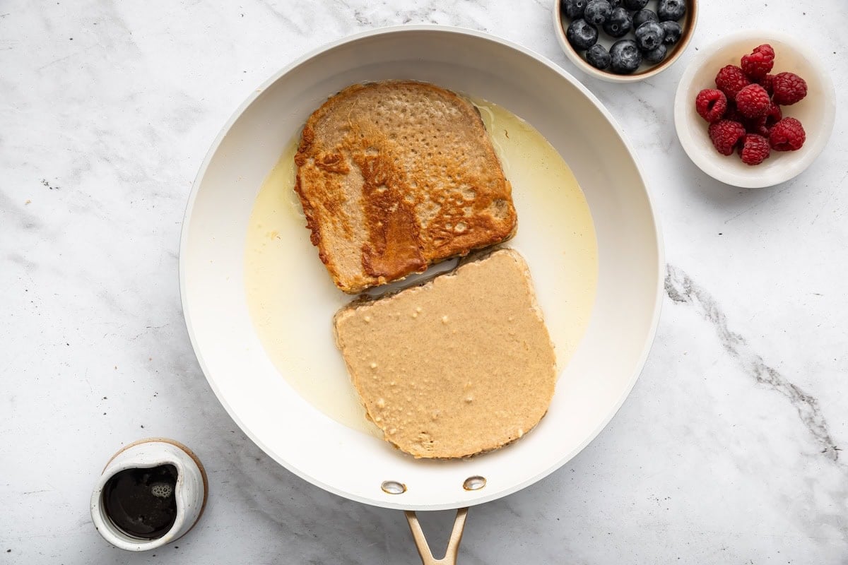 Bread soaking in protein French toast mixture in skillet.