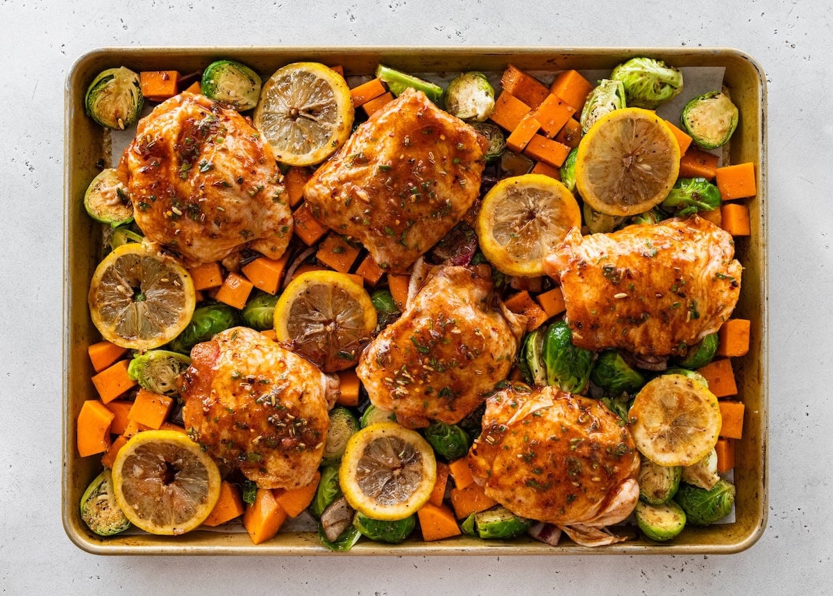 Sheet pan chicken thighs Sheet pan chicken thighs surrounded by roasted Brussels sprouts, squash, and sliced lemon.