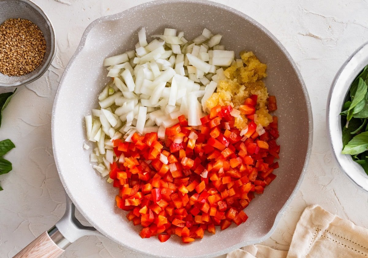 Diced onion, bell pepper and minced garlic added to a skillet before saut&eacute;ing.