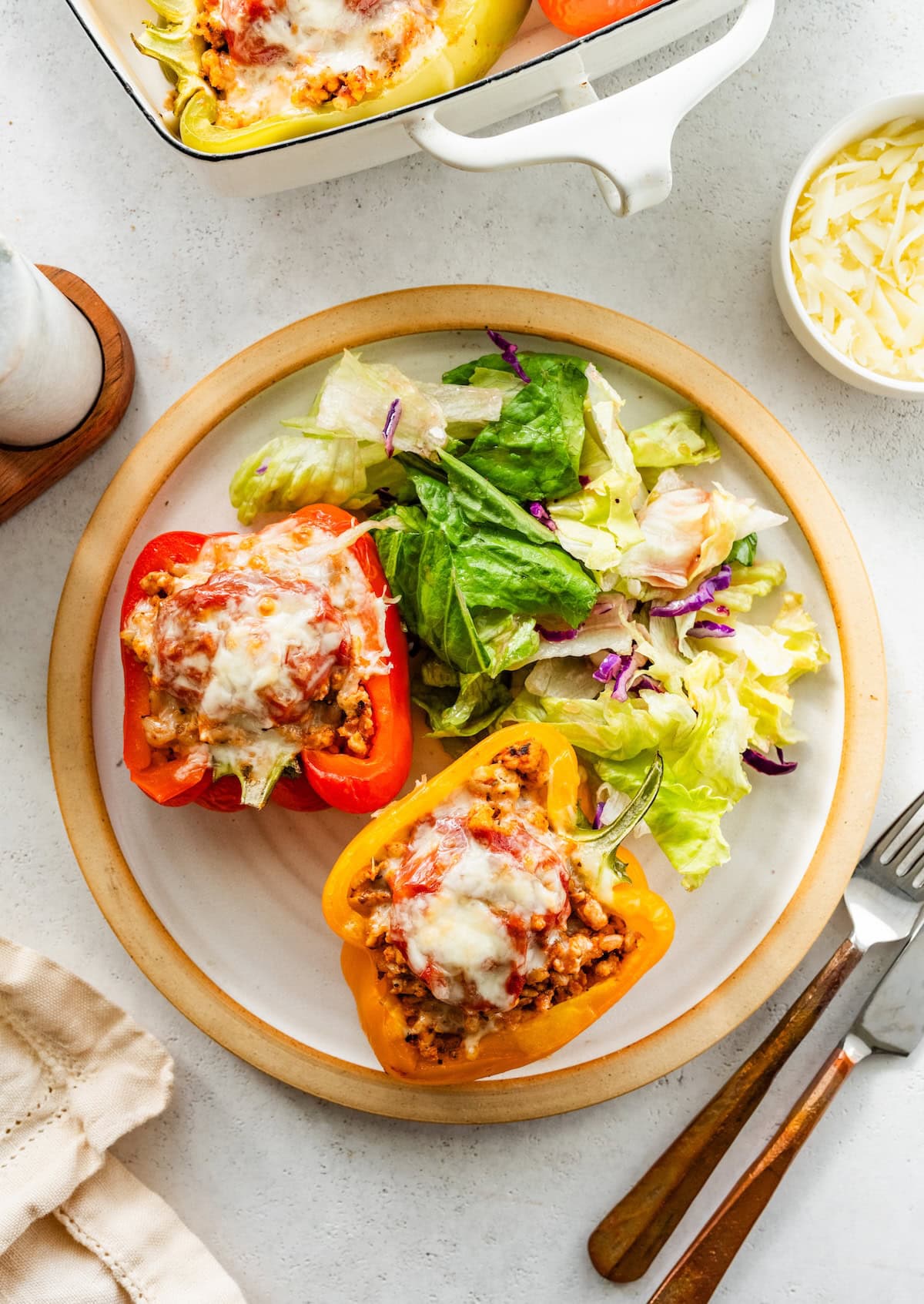 A serving of two turkey stuffed bell peppers on a plate with a side salad.