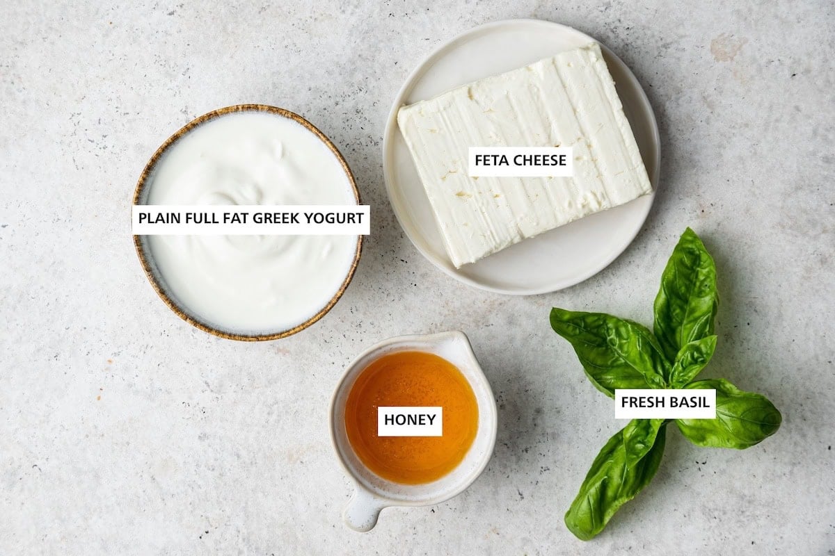 Ingredients measured out to make Whipped Feta Dip: plain full fat Greek yogurt, honey, feta cheese and fresh basil.